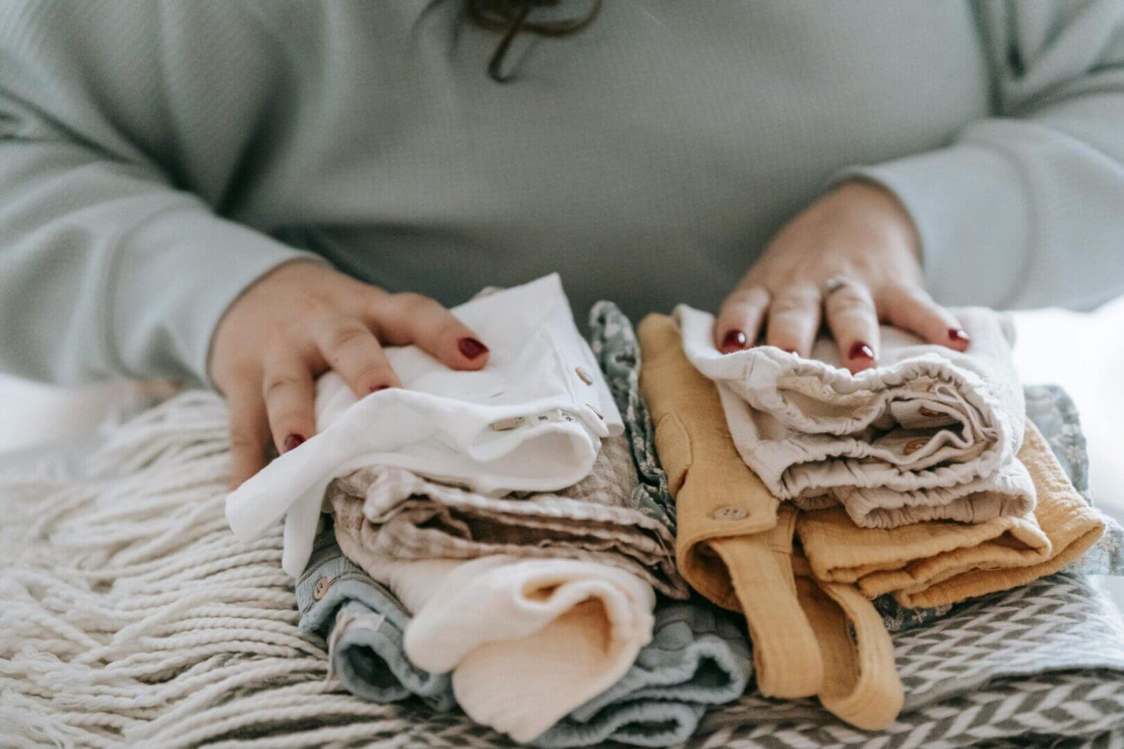 A person is folding clothes on the bed